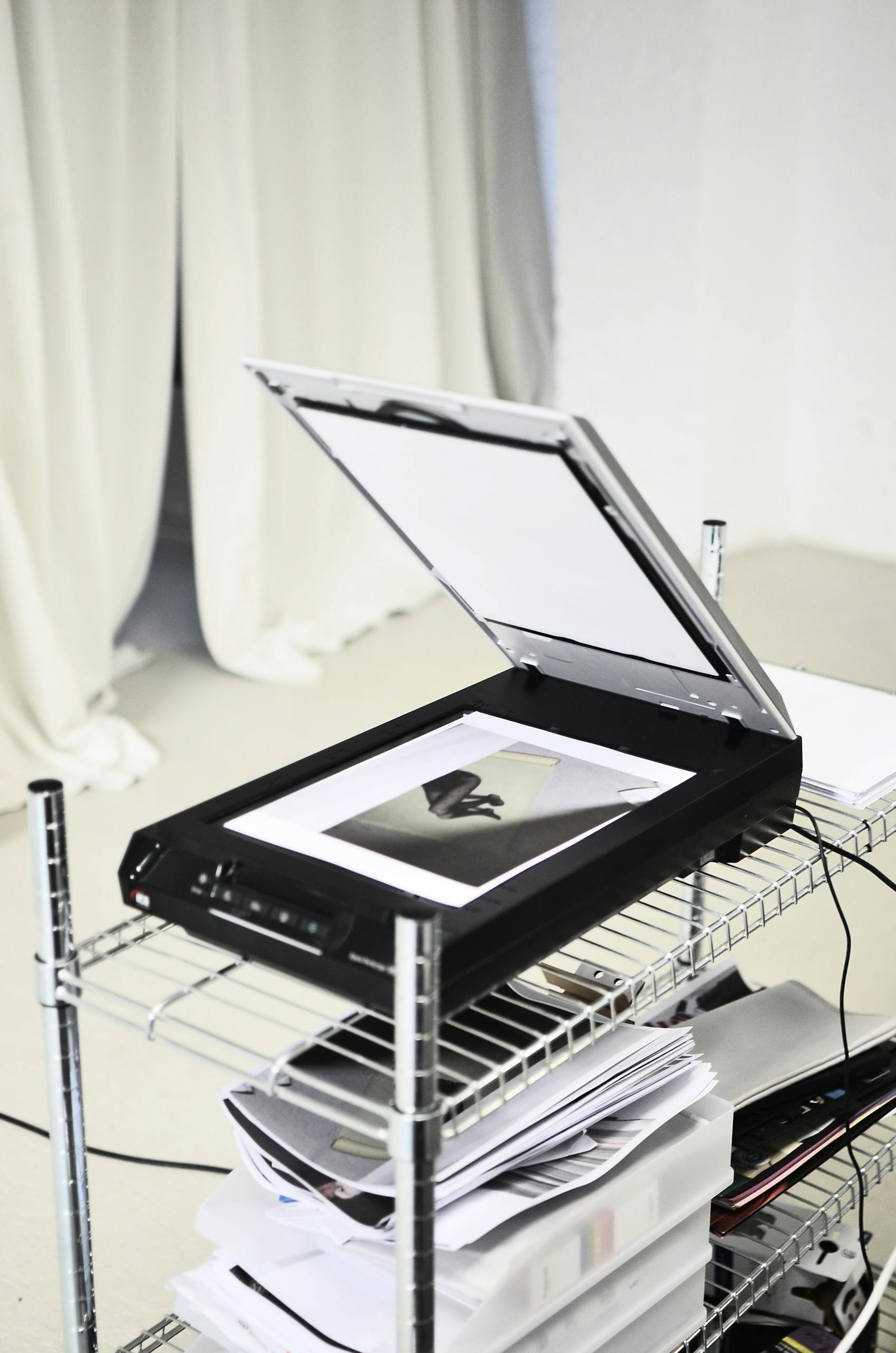 An open scanner on a metal shelf in a minimalist office, displaying a monochrome image.