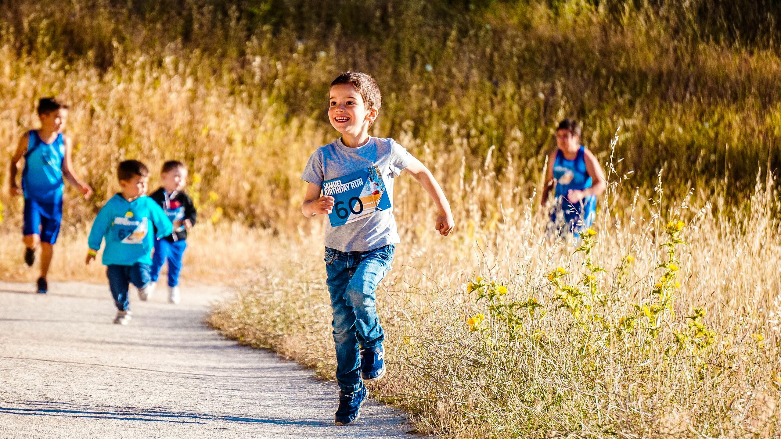 Children joyfully running in a park during a cheerful outdoor race event.
