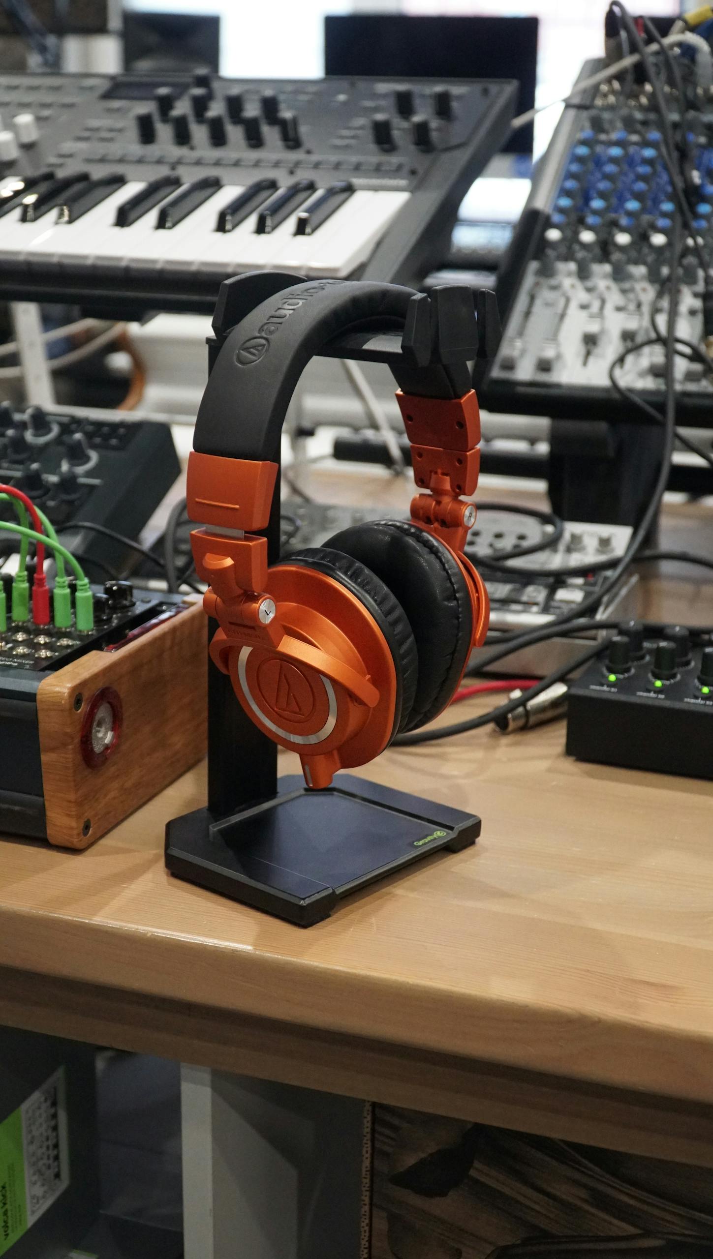 Bright orange headphones on a stand in a modern audio studio with mixing equipment. audio technica