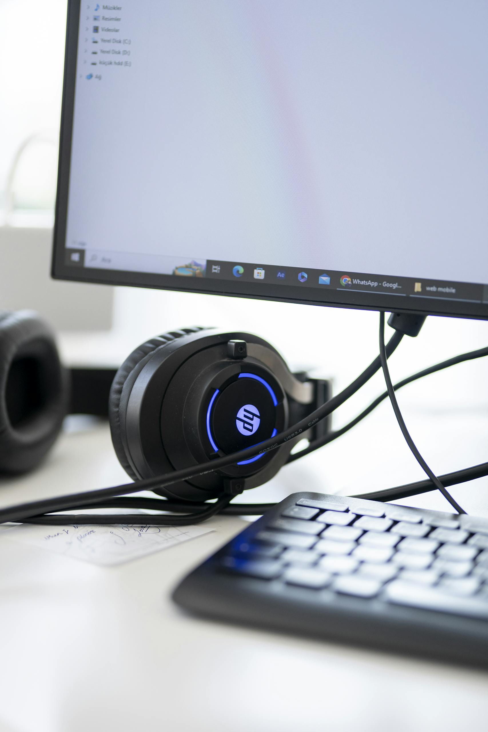 Close-up view of a modern workspace setup featuring headphones, monitor, and keyboard.