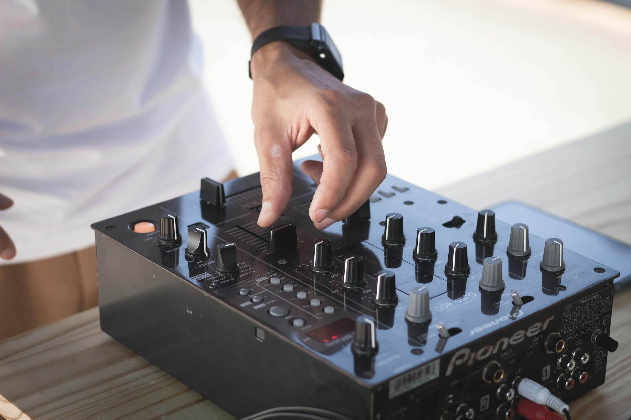 DJ adjusting sound levels on Pioneer controller during an outdoor music session.