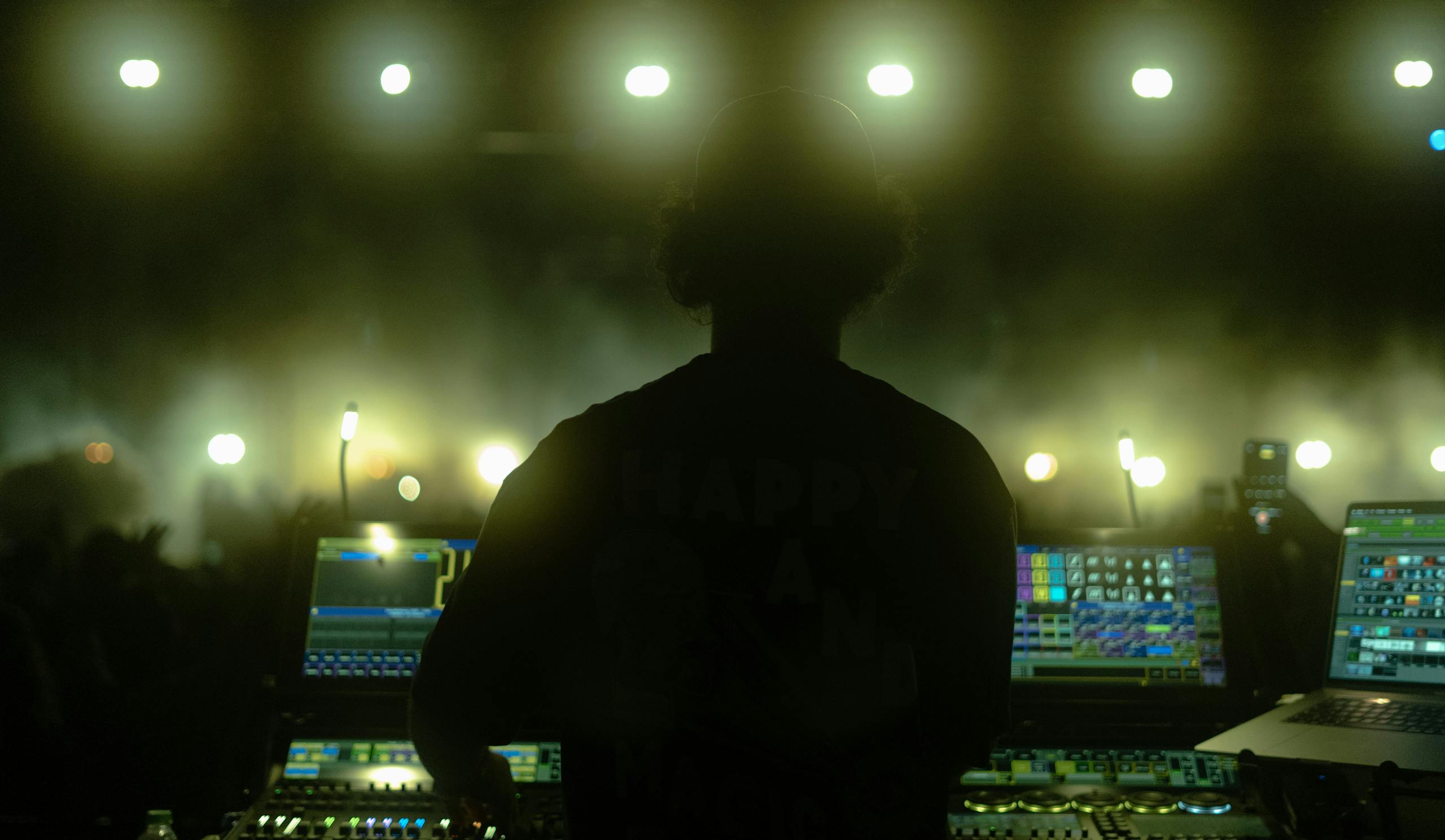 Silhouette of a DJ performing at a vibrant Istanbul nightclub with bright stage lights.