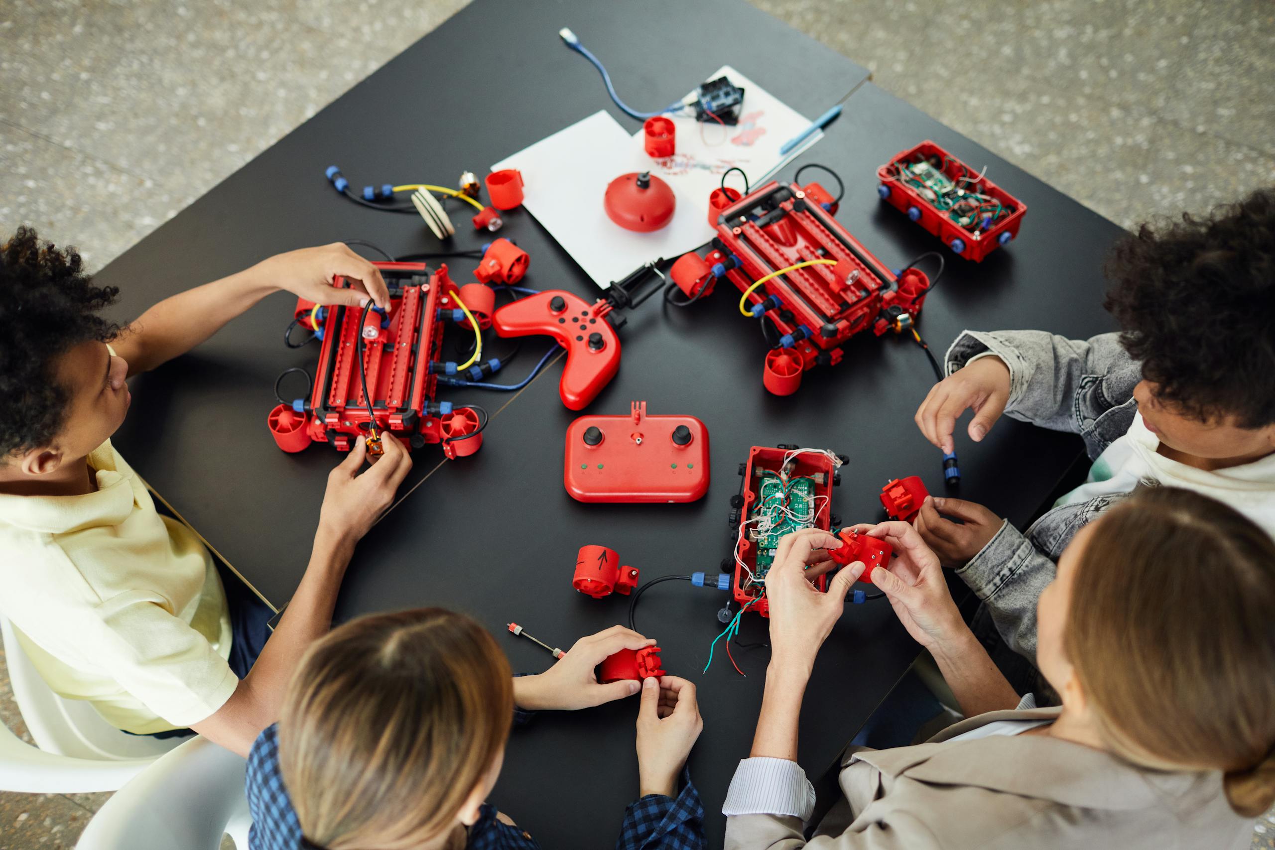 Group of children learning electronics and robotics with toys on a table, engaging in hands-on activities.