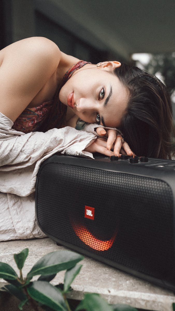 Young woman rests beside a portable speaker outdoors in İstanbul, capturing a serene moment.