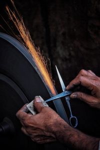 person sharpening gray scissors
